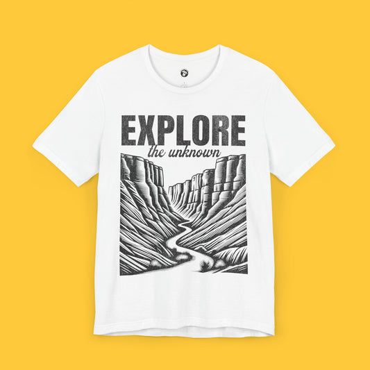 T-shirt featuring a landscape silhouette of a canyon with a winding path and the quote "Explore the Unknown."