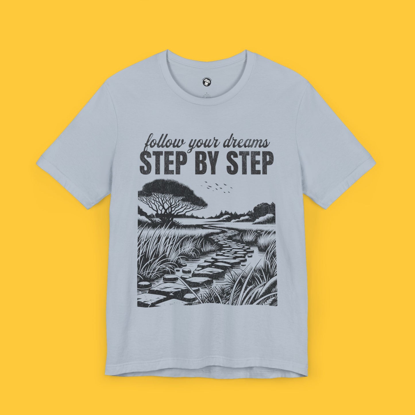 T-shirt with a minimalist landscape silhouette and the quote "Follow your dreams, step by step" in bold text.