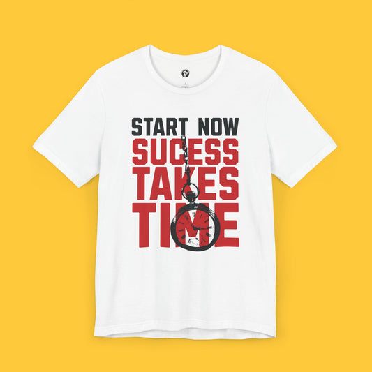 White t-shirt with bold red and black text "Start Now, Success Takes Time" featuring a simple black clock graphic.