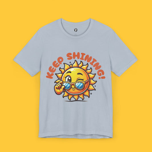 T-shirt featuring a cheerful sun character wearing sunglasses with the quote "Keep Shining!" in a playful font.