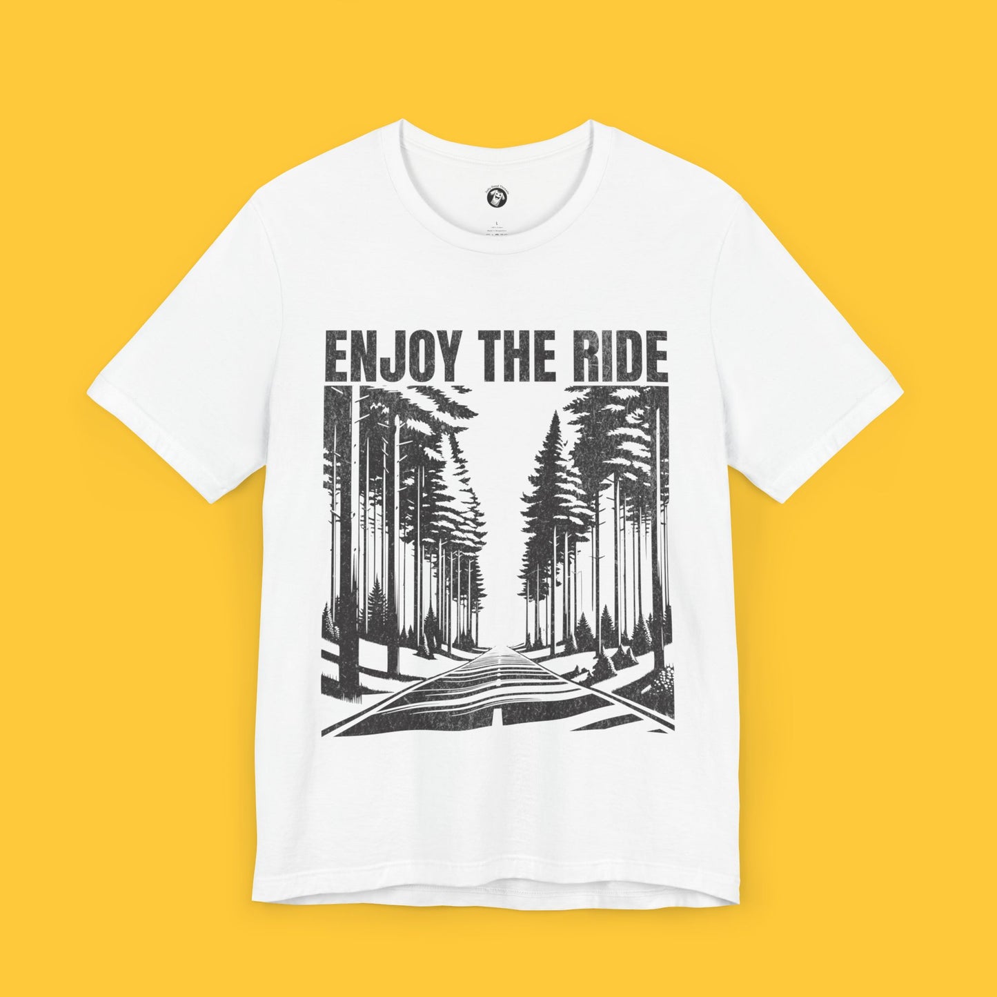 T-shirt featuring a landscape silhouette of a road through tall pine trees with the quote "Enjoy the Ride," symbolizing life's journey.