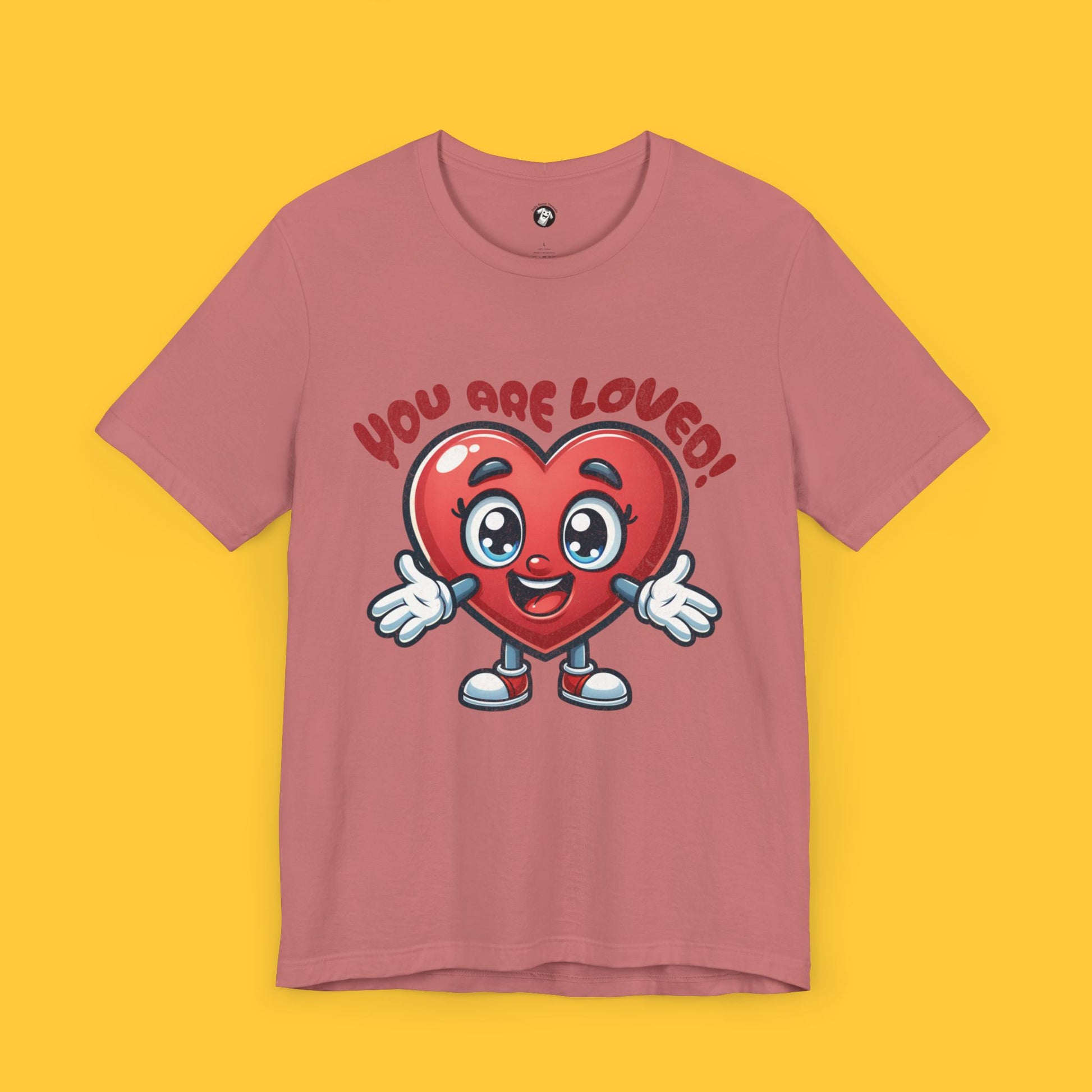 T-shirt with a cute heart character reaching out for a hug and the quote "You Are Loved!" in a bubbly font.